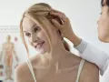Dermatolog bada skórę głowy pacjentki, delikatnie dotykając jej włosów.