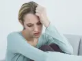 Zmartwiona kobieta z ręką na czole, symbolizująca niechęć do pracy i depresję.