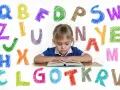 Dziewczynka z orzeczeniem o dysleksji skupiona na książce, otoczona kolorowymi literami alfabetu.