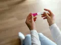 Dłonie trzymające test ciążowy, symbol nadziei i pierwszych objawów ciąży.