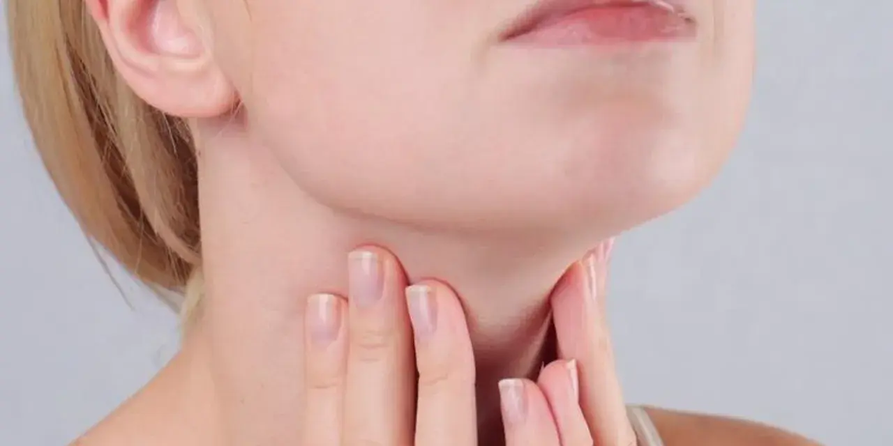 Kobieta dotyka szyi, gdzie znajduje się tarczyca. Wyniki badań wskazują na ft3 podwyższone tsh w normie, co może wymagać dalszej diagnostyki.