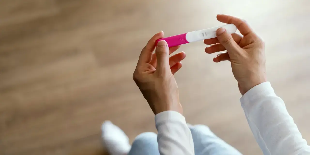 Dłonie trzymające test ciążowy, symbol nadziei i pierwszych objawów ciąży.