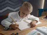 Chłopiec pisze w zeszycie, ćwicząc jak wytłumaczyć dziecku dodawanie i odejmowanie do 20.