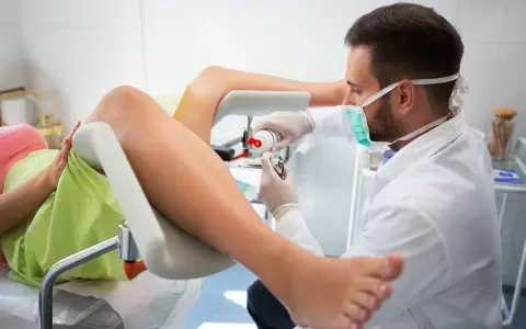 Lekarz w masce i rękawiczkach aplikuje octenisept na krocze po porodzie.