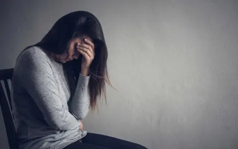 Kobieta zamyślona, z ręką na czole. Obraz symbolizuje trudności w zrozumieniu, jak wspierać osobę z depresją na odległość.