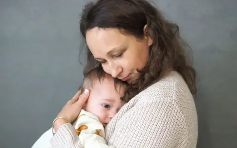 Mama tuli tulą do siebie dziecko, łagodząc lęk separacyjny u niemowlaka.
