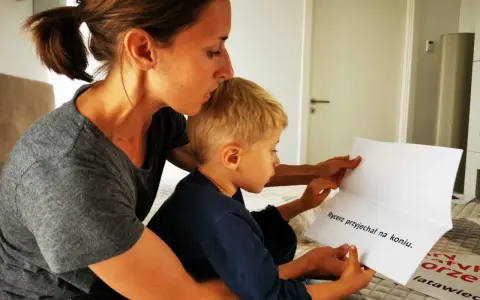 Mama pomaga synkowi czytać zdanie "Rycerz przyjechał na koniu". To świetny sposób, jak nauczyć dziecko szybko czytać.