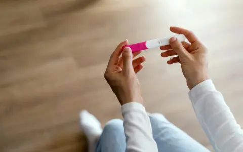 Dłonie trzymające test ciążowy, symbol nadziei i pierwszych objawów ciąży.