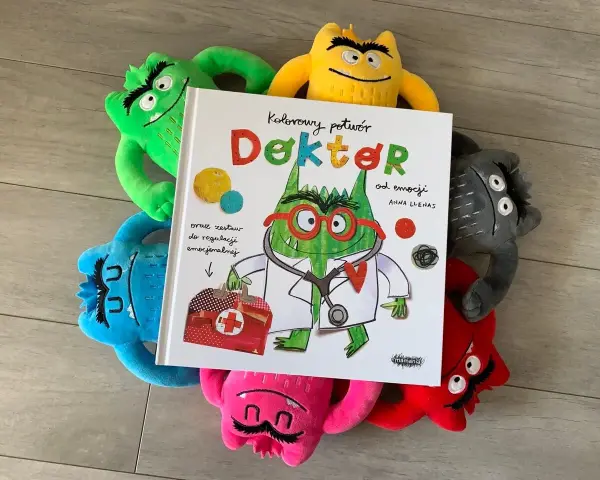 Kolorowy potwór Doktor od emocji, otoczony pluszowymi potworami, czeka na przedszkole.