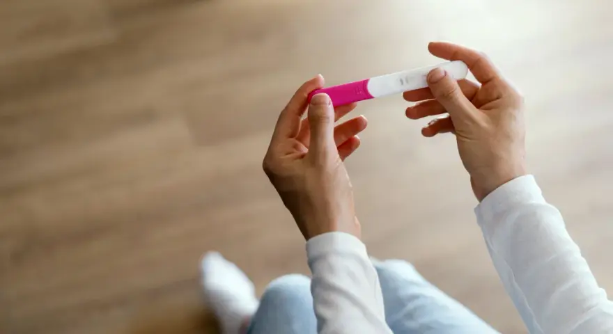 Dłonie trzymające test ciążowy, symbol nadziei i pierwszych objawów ciąży.