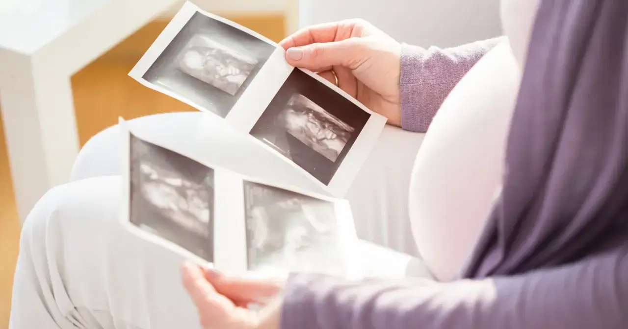 Kobieta po 30. roku życia ogląda zdjęcia USG swojego dziecka.