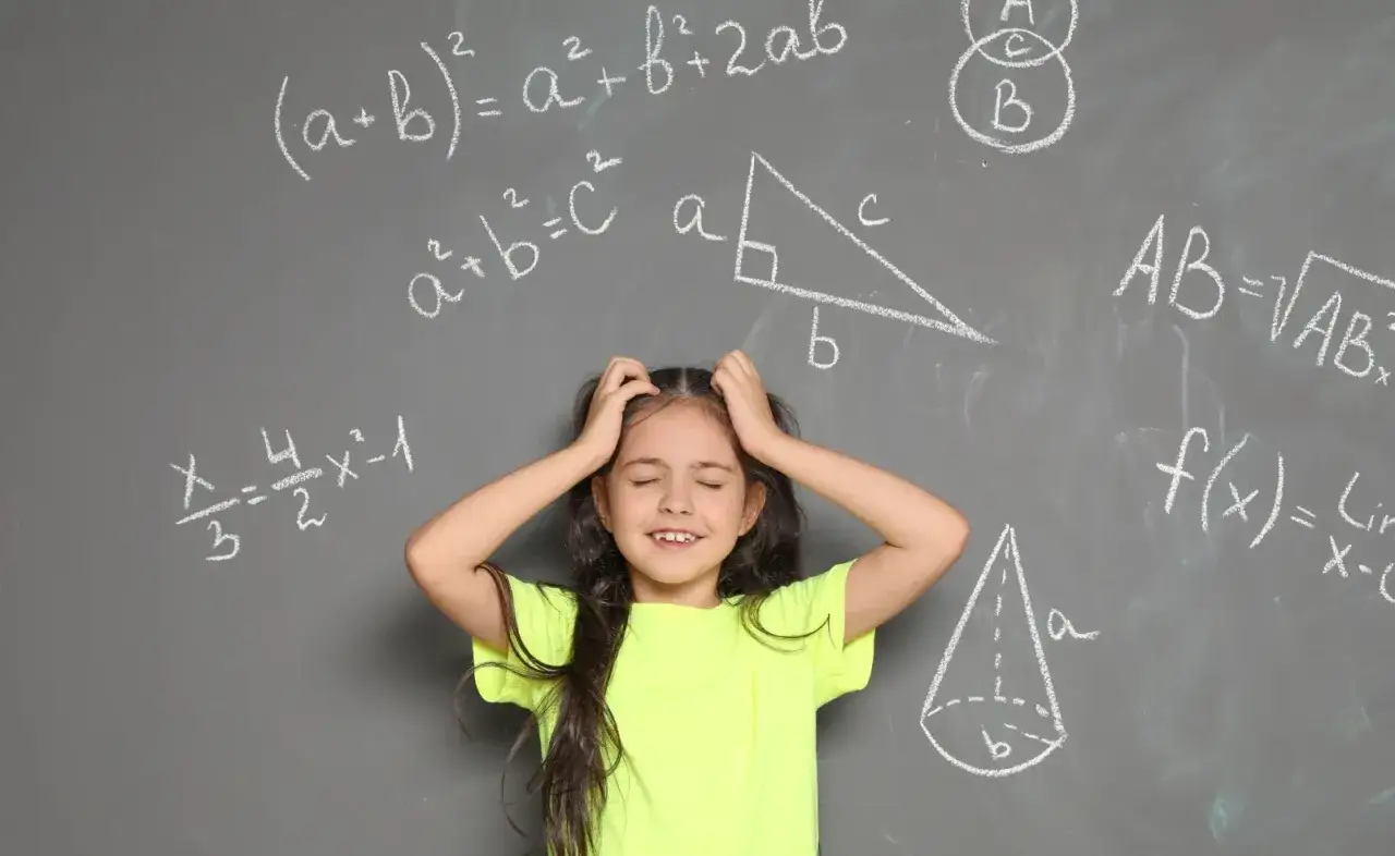 Dziewczynka zmagająca się z matematyką, wzory na tablicy. Jak zrozumieć matematykę?