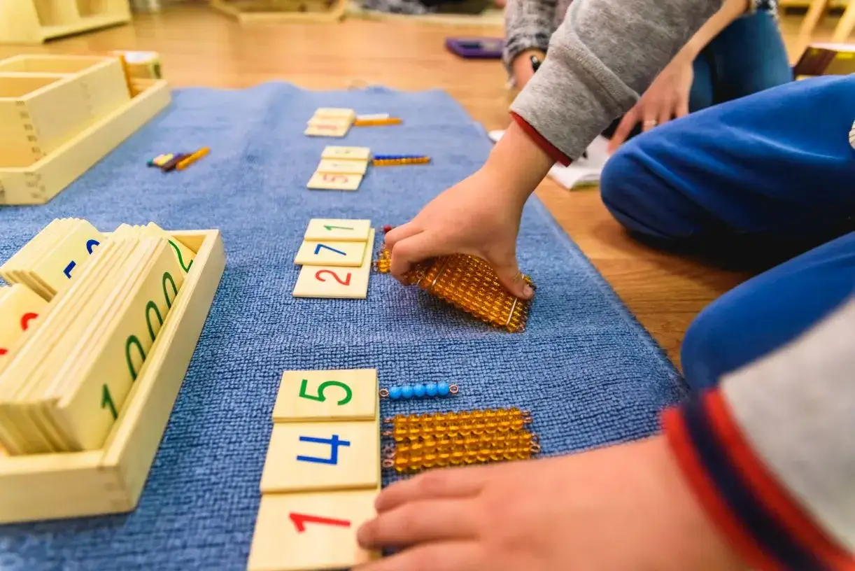 Dziecko układa koraliki i karty z cyframi, ucząc się matematyki.