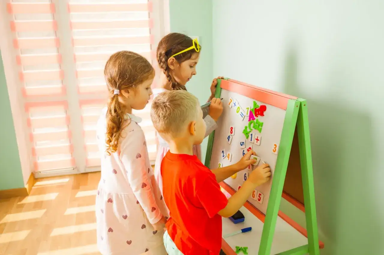 Dzieci uczą się matematyki, układając cyfry i znaki na tablicy. Zabawa z liczbami to świetny sposób, jak nauczyć się matematyki.